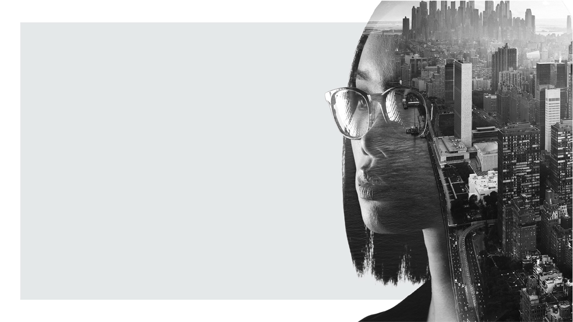 Double exposure portrait of a woman wearing glasses, with a black-and-white city skyline blended into her profile.