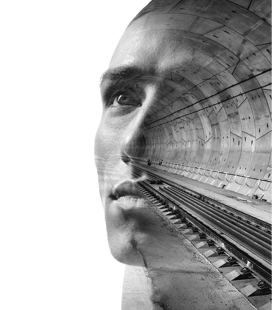 Double exposure portrait of a man looking upward, with the interior structure of a modern tunnel overlaid across his face.